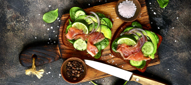 Geröstetes Brot mit geräuchertem Lachs, Gurke und Avocado